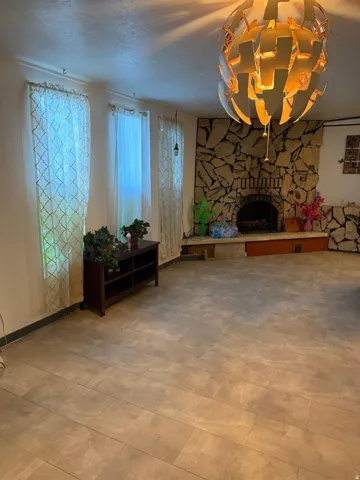 Spacious room featuring tile flooring, a stone fireplace, and an oversized decorative light fixture