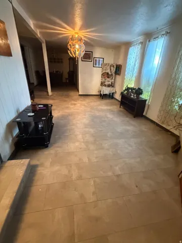 Spacious living area featuring large format tile flooring and a distinctive central ceiling fixture