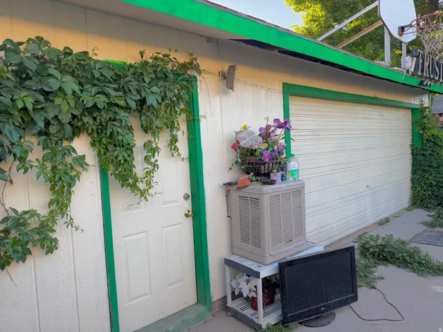 Exterior wall featuring white siding with green trim, a white entry door, and an overhead garage door