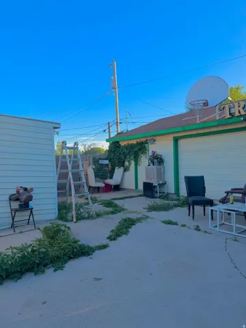 Detached garage structure featuring a white roll-up door, green trim, and a basketball hoop