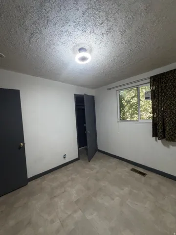 Room featuring wood-finish flooring, a ceiling-mounted light fixture, and a window offering natural illumination