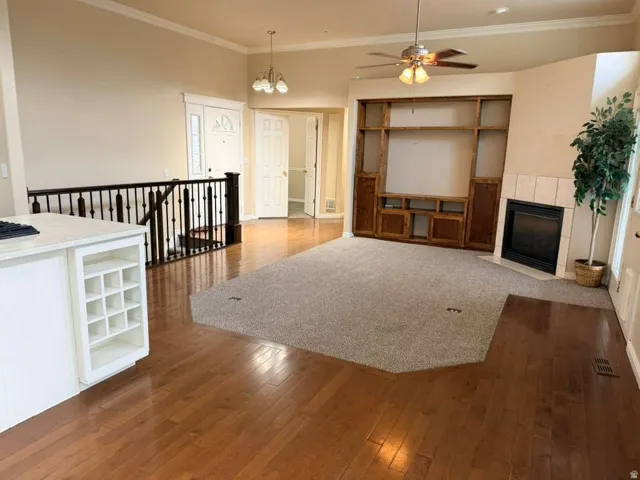 Expansive living area featuring hardwood and carpet flooring, a corner fireplace with tile surround, and built-in wood cabinetry