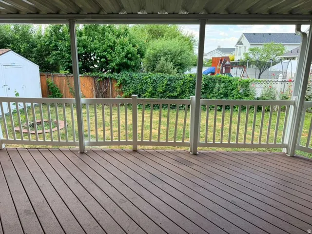 Covered deck featuring wood-finish flooring and white railing