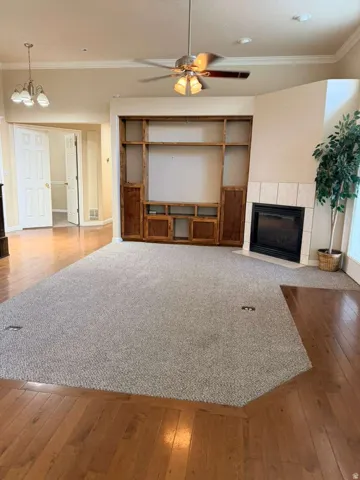 Spacious living area featuring a built-in entertainment center, a corner fireplace with tile surround, and a ceiling fan