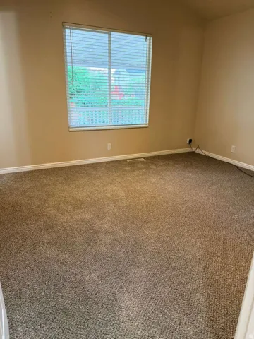 Carpeted room with a single window featuring horizontal blinds