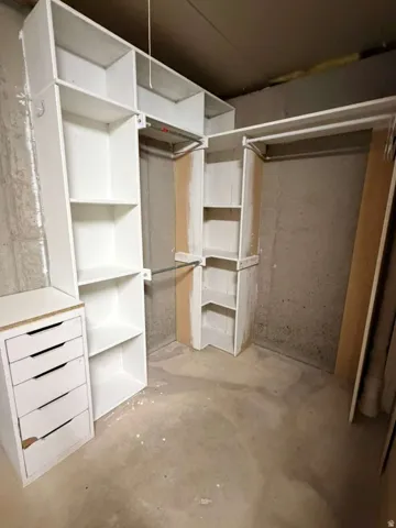 Customizable closet system featuring white shelving, multiple hanging rods, and a drawer unit for organized storage