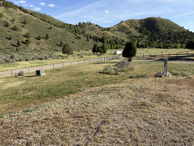 Expansive open land with a gravel road, bordered by a wooden fence