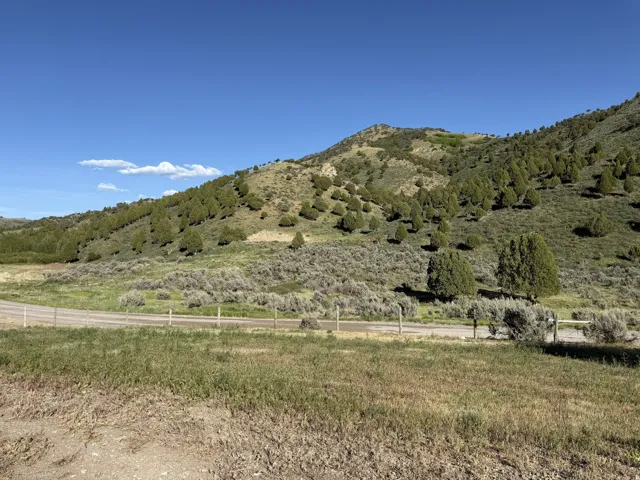 Expansive open land with a distinct gravel road, bordered by a rustic wire fence