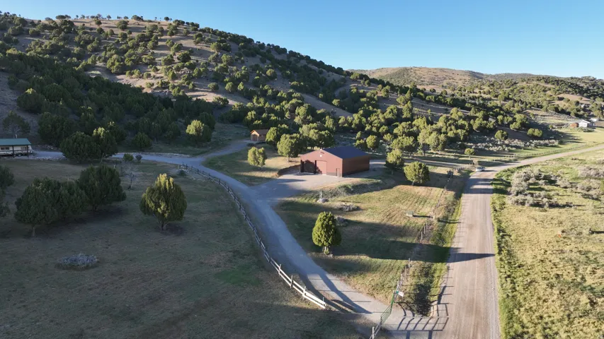 Expansive property featuring multiple structures, including a brown barn-style building and a single-story residence with a covered porch