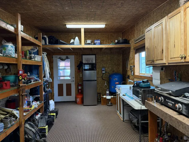 Utility room featuring wood paneling, wall-mounted cabinetry, built-in shelving, a window, and patterned flooring