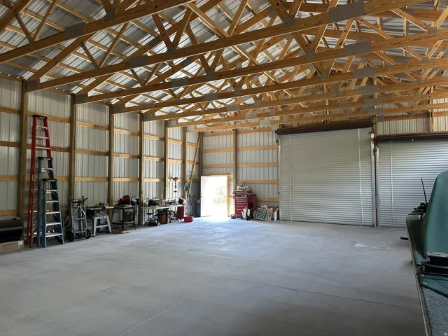 Spacious interior featuring exposed wood truss ceiling, metal panel walls, and a finished concrete floor