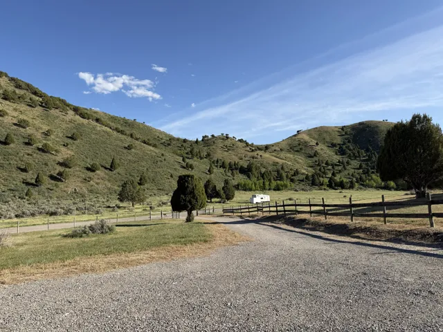 Expansive mountain-backed property featuring a gravel driveway and partial wood fencing