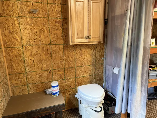 Wood-finish oriented strand board walls with a natural wood cabinet featuring dark hardware