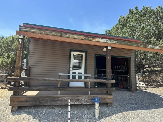 Outbuilding with tan horizontal siding, covered porch, and dual-pane windows