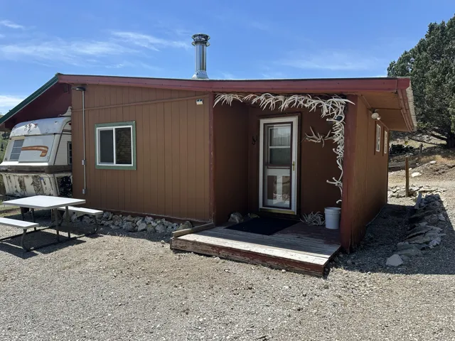 Cabin exterior featuring horizontal wood siding, a metal chimney, and a covered entry porch
