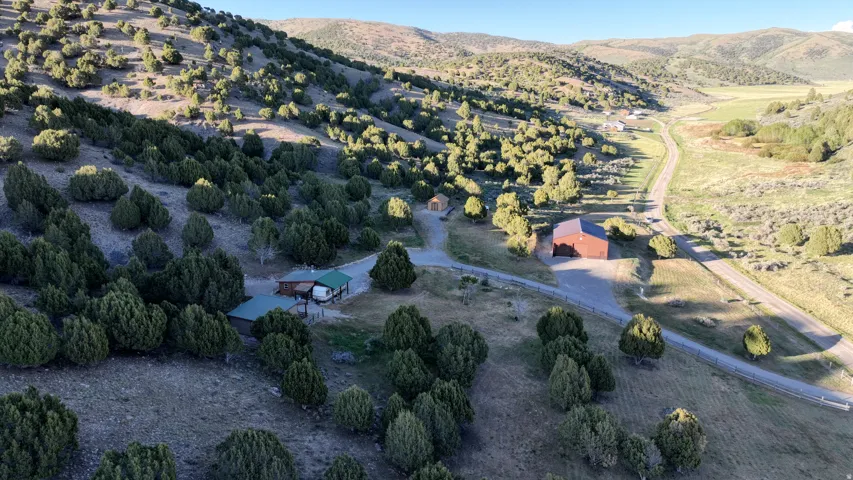 Extensive acreage featuring multiple structures including a brown-roofed residence, a large brown barn-style building, and a smaller brown outbuilding