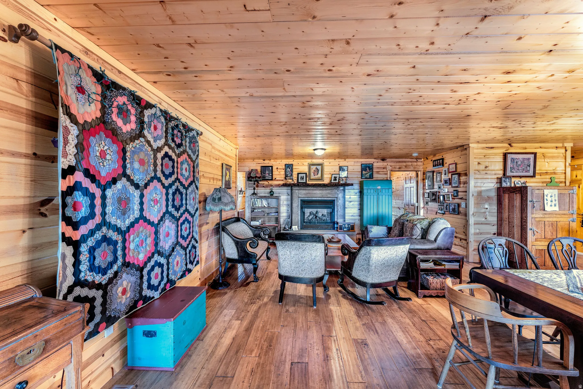 Expansive wood-paneled room featuring wood-finish flooring, a built-in fireplace with a stone surround, and wood-paneled walls and ceiling