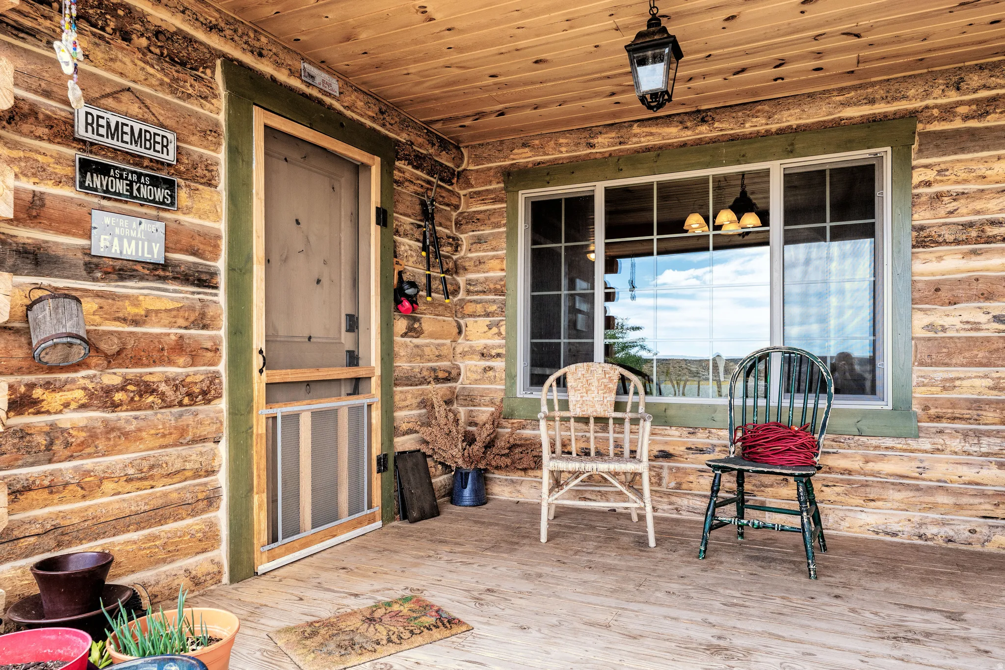 Covered porch featuring log-cabin siding, a wood-finish ceiling, and natural wood flooring