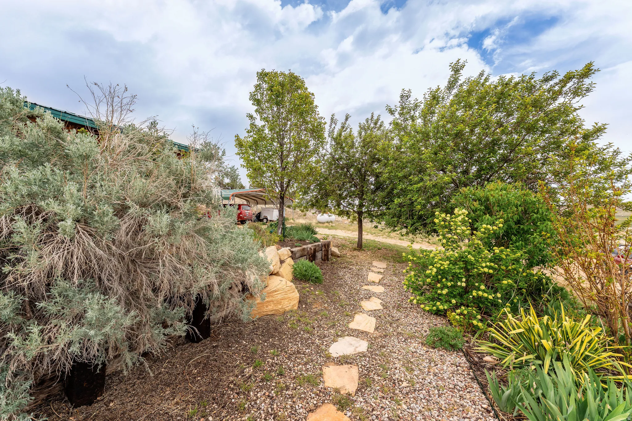 Landscaped pathway featuring flagstone pavers, mature trees, and diverse shrubbery
