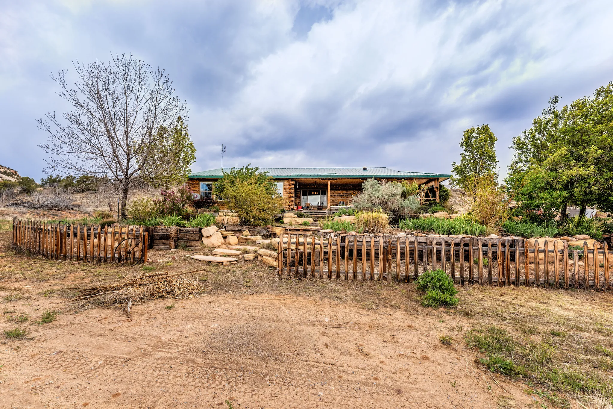Log cabin exterior with a green metal roof, featuring a covered porch entry