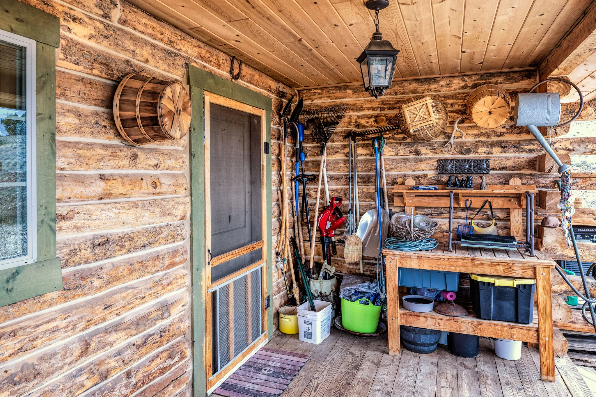 Covered porch featuring log-cabin style walls, a wood-plank ceiling, and wood flooring
