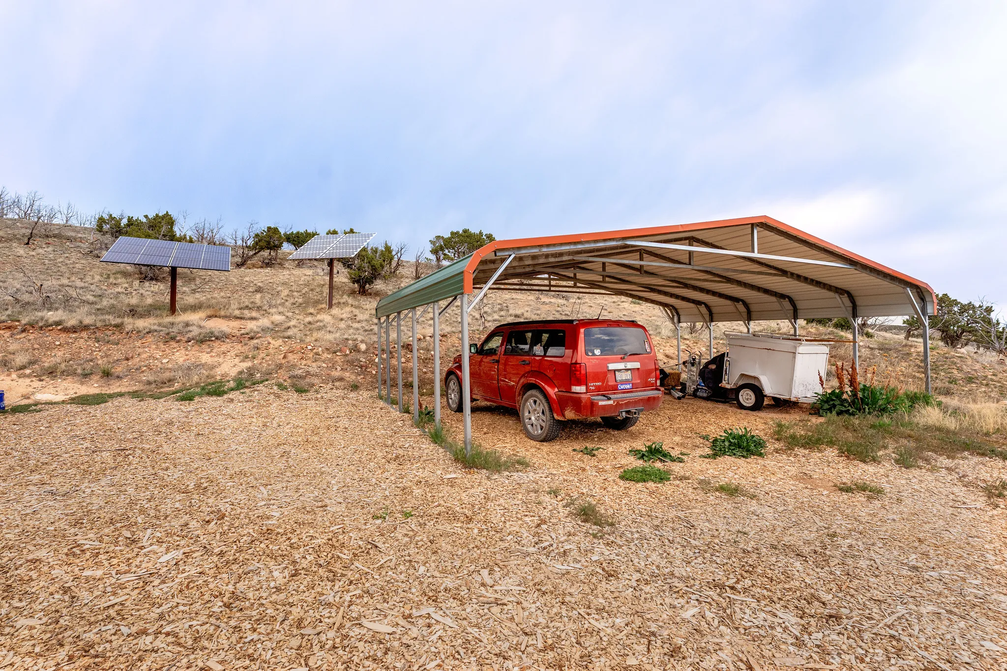Gravel parking area fehttps://www.utahrealestate.com/lip.wizard/run/step/2/hbid/5380820#aturing a metal carport and two ground-mounted solar panel arrays