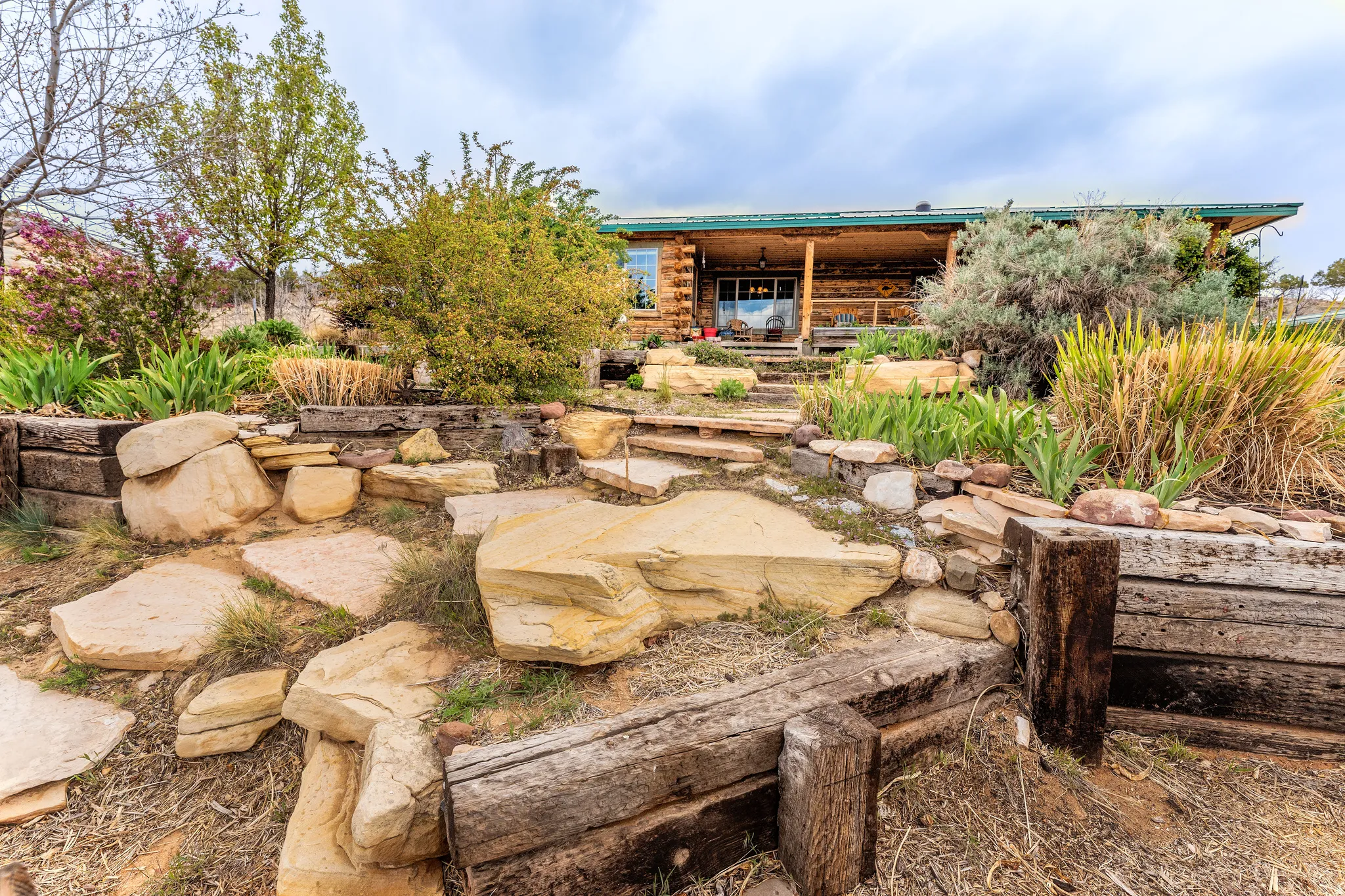 Log cabin exterior featuring a covered porch, natural wood siding, and a green metal roof