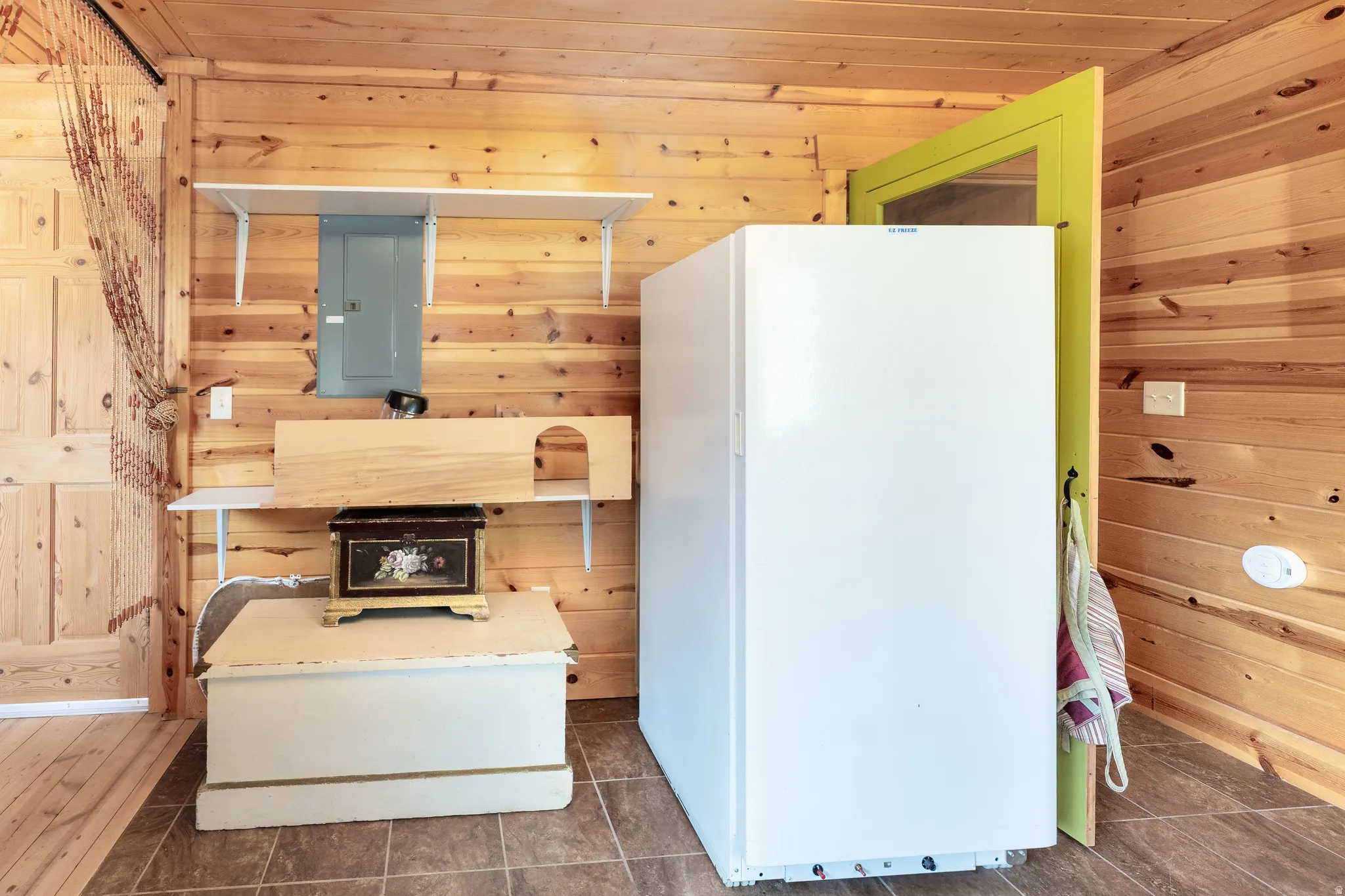 Interior space featuring wood paneling throughout, a white freestanding refrigerator, and durable tile flooring