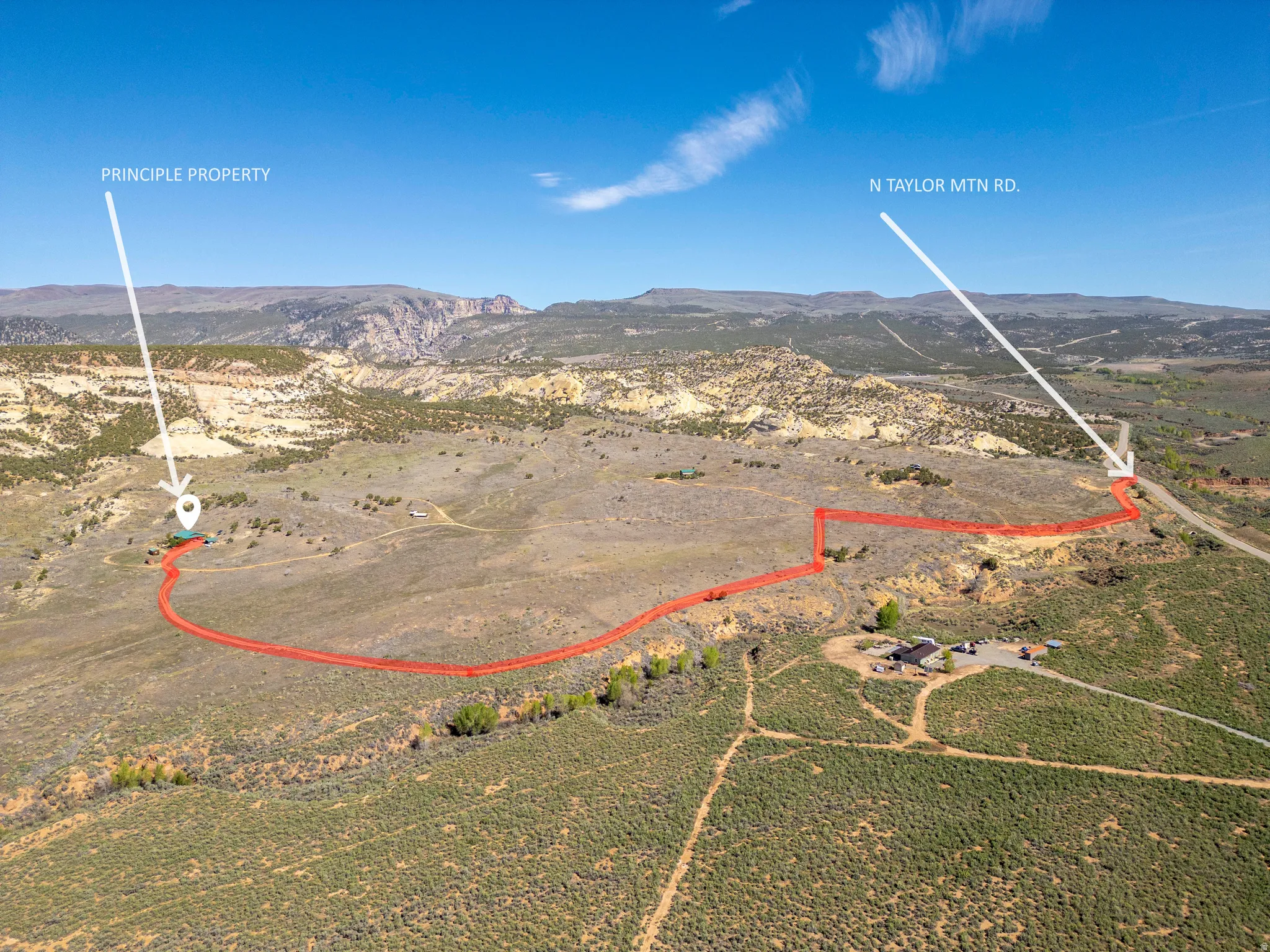 Expansive acreage with established property boundaries, featuring a building site, natural terrain, and distant mountain backdrops