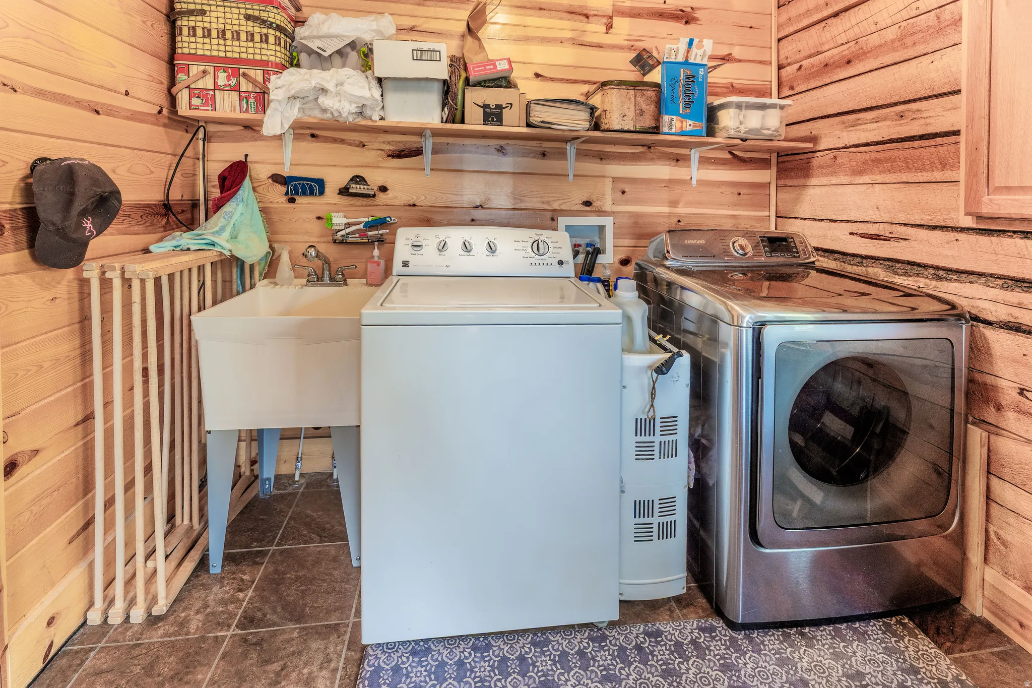 Utility space featuring wood paneling, a white utility sink, and durable tile flooring