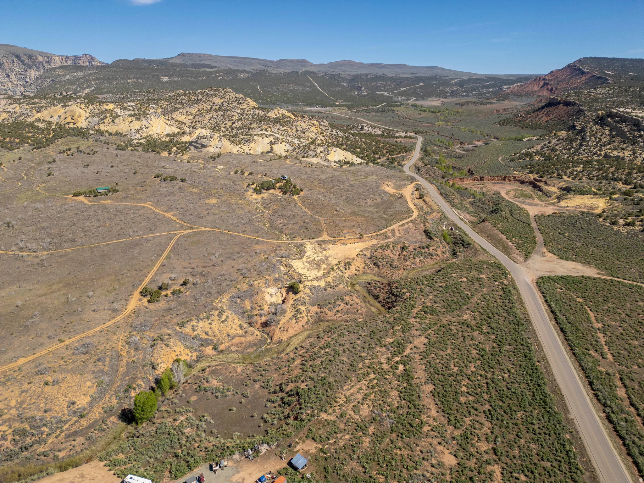 Expansive undeveloped land featuring a paved road, natural terrain, and distant mountain ranges
