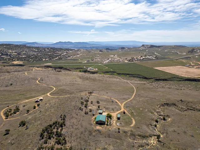 Expansive rural property featuring multiple structures, extensive unpaved driveways, and surrounding natural terrain