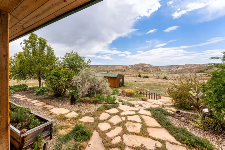 Expansive outdoor space featuring a flagstone pathway, mature trees, and natural landscaping