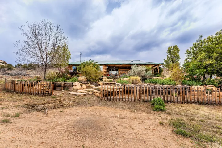 Log cabin exterior with a green metal roof, featuring a covered porch entry