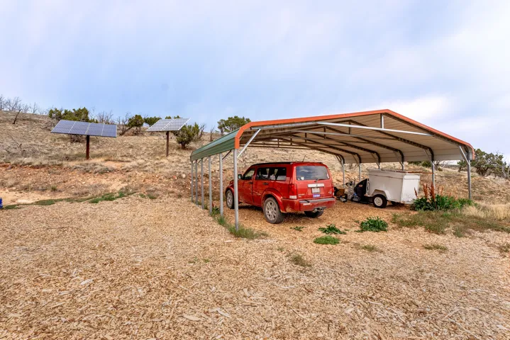 Gravel parking area fehttps://www.utahrealestate.com/lip.wizard/run/step/2/hbid/5380820#aturing a metal carport and two ground-mounted solar panel arrays