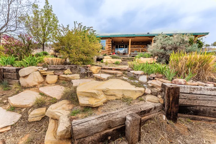 Log cabin exterior featuring a covered porch, natural wood siding, and a green metal roof