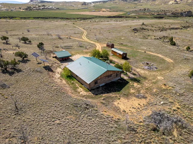 Log cabin residence with a green metal roof situated on a expansive rural property
