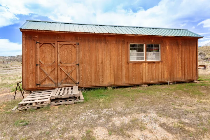 Wood-sided storage building with a green metal roof