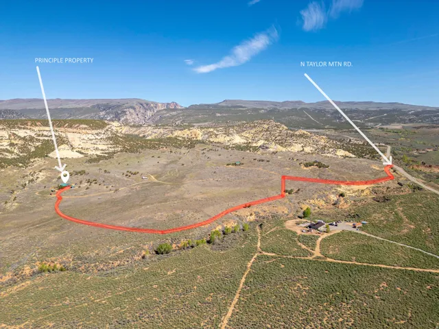 Expansive acreage with established property boundaries, featuring a building site, natural terrain, and distant mountain backdrops