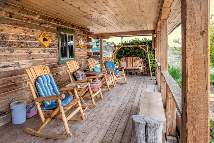 Expansive covered porch featuring a rustic wood ceiling, log-style exterior wall, and wood-plank flooring
