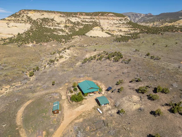 Aerial property overview featuring a main residence with a green roof, a detached ancillary building, and a separate shed