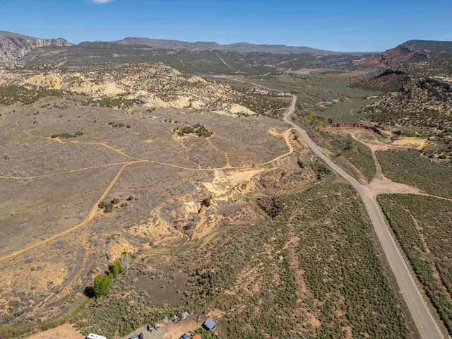 Expansive undeveloped land featuring a paved road, natural terrain, and distant mountain ranges