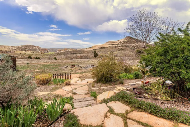 Stone pathway leading to a fenced garden area with varied plantings