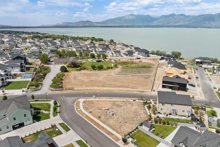 Aerial perspective showcasing a residential community with lake frontage and mountain backdrop