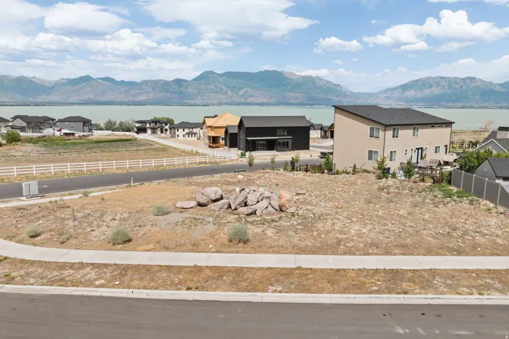 Expansive undeveloped lot featuring street frontage, a concrete sidewalk, and surrounding residential properties