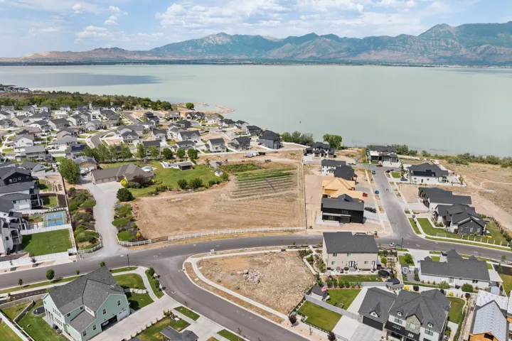 Aerial perspective showcasing a residential development alongside a large body of water, with mountains in the background