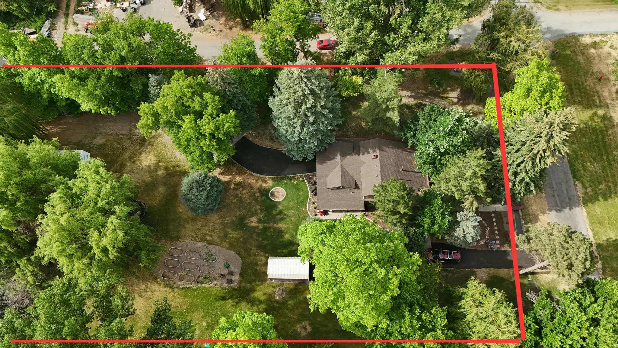 Expansive lot featuring mature trees, a private driveway, garden beds, and a detached structure