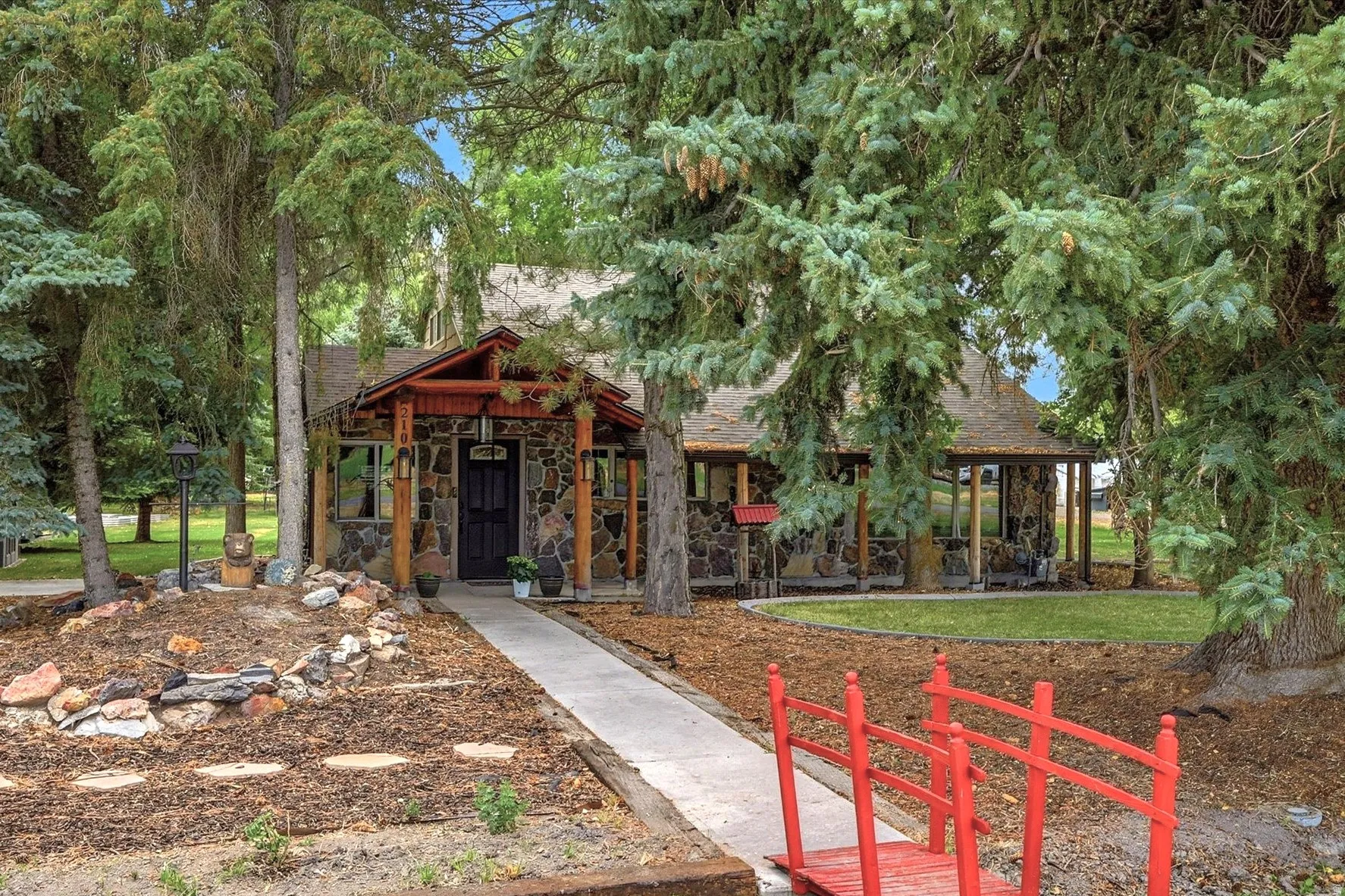 Stone façade residence with a covered entry porch, supported by wood posts and beams