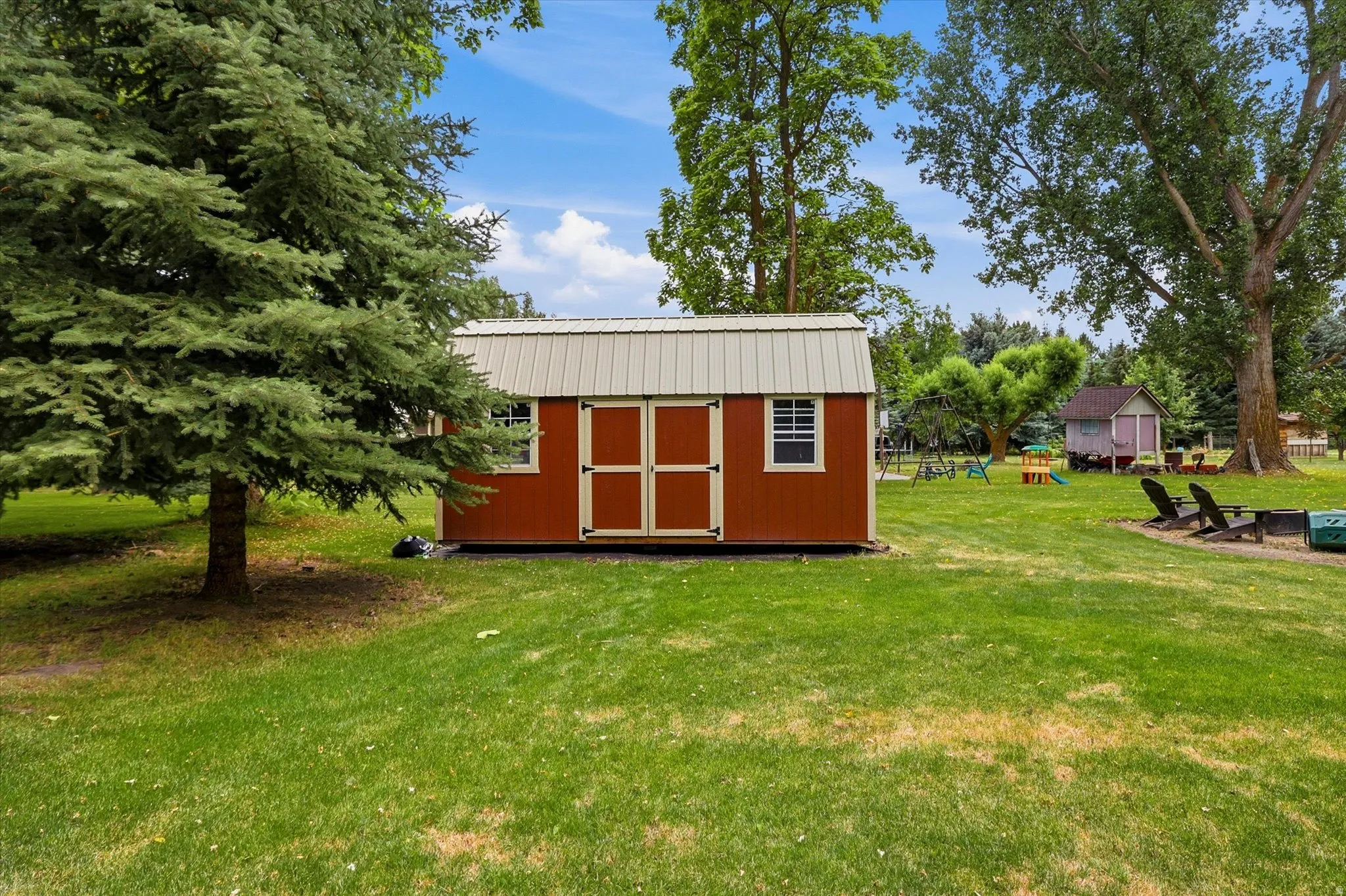 Spacious backyard featuring a red storage shed with a metal roof, double entry doors, and two windows