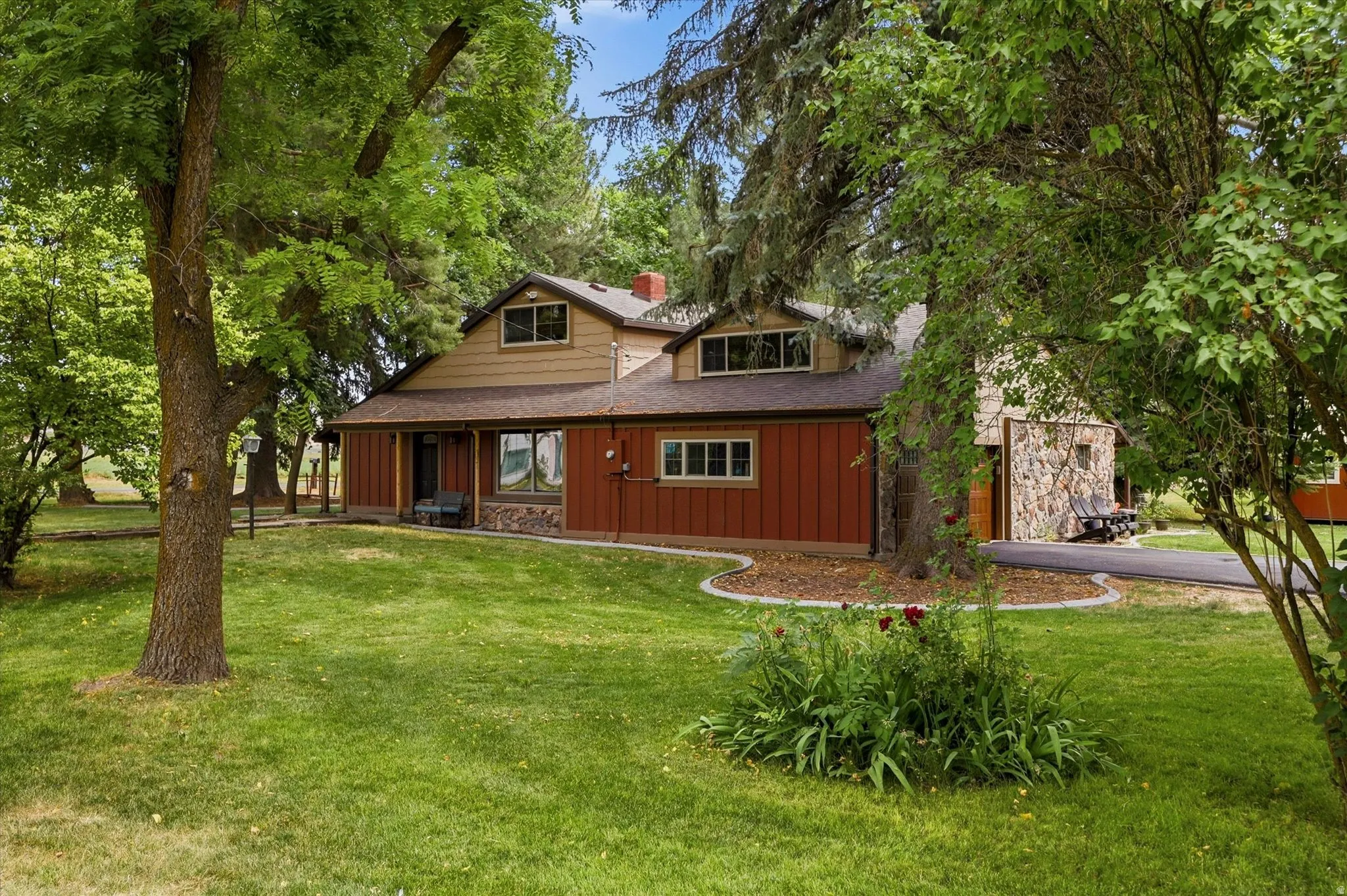 Exterior with a two-tone facade featuring red siding and light brown upper story siding, stone veneer accents, and a dark shingle roof